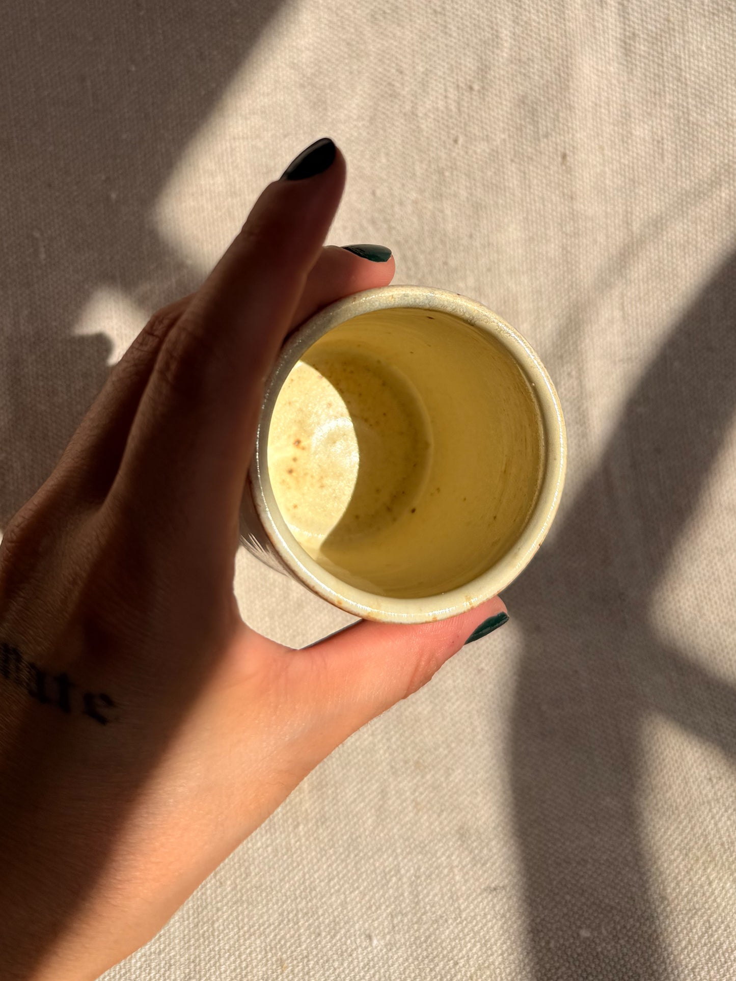 Hand holding a small yellow container with a light background
