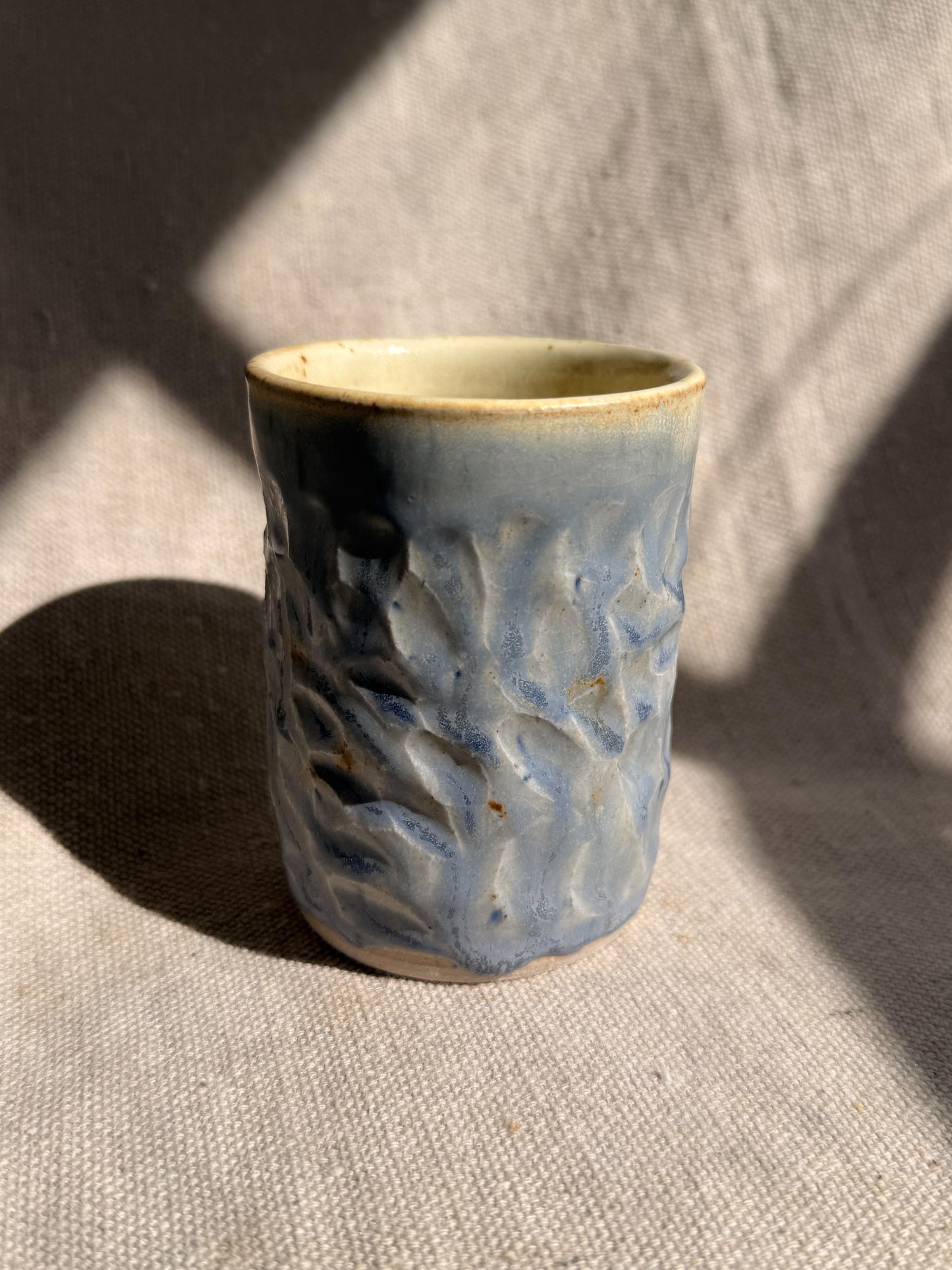 Ceramic cup with textured design on a textured surface