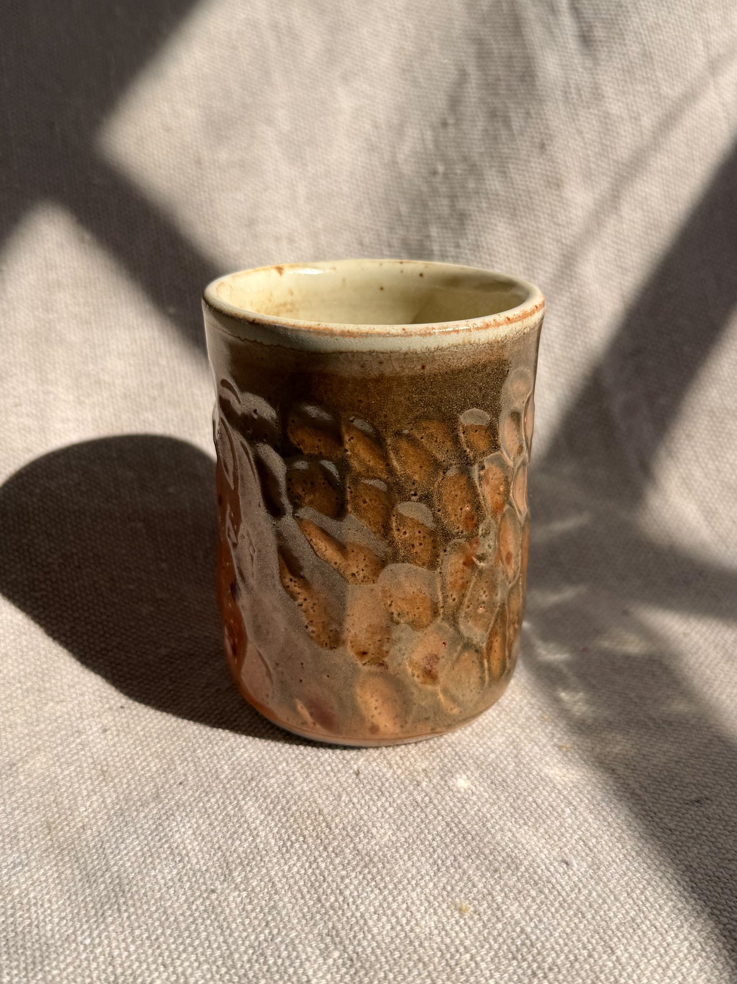 Ceramic cup with textured surface on a textured fabric background