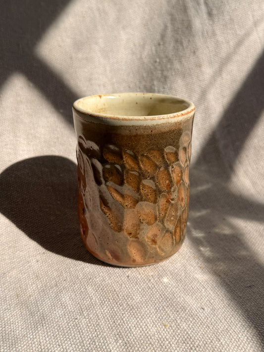 Ceramic cup with textured surface on a textured fabric background