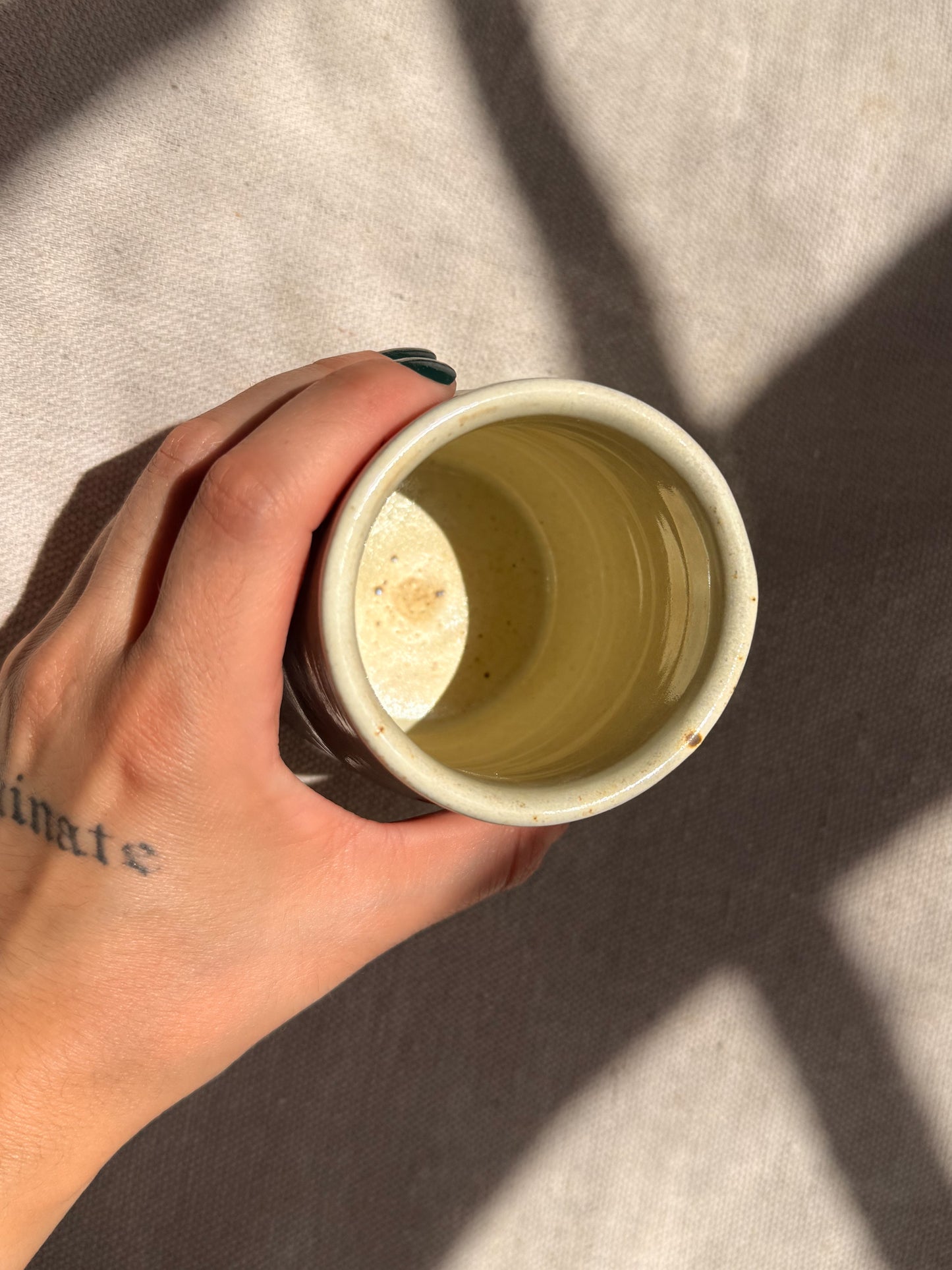 Hand holding a white ceramic mug with a textured interior against a neutral background