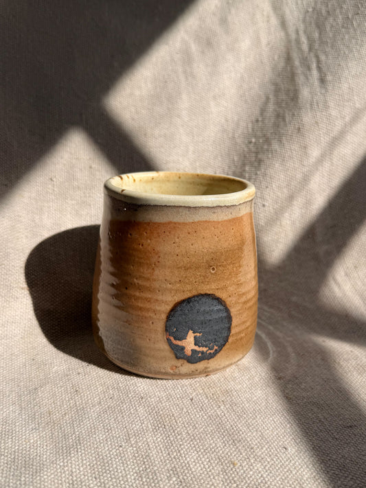 Ceramic cup with a blue design on a textured beige surface