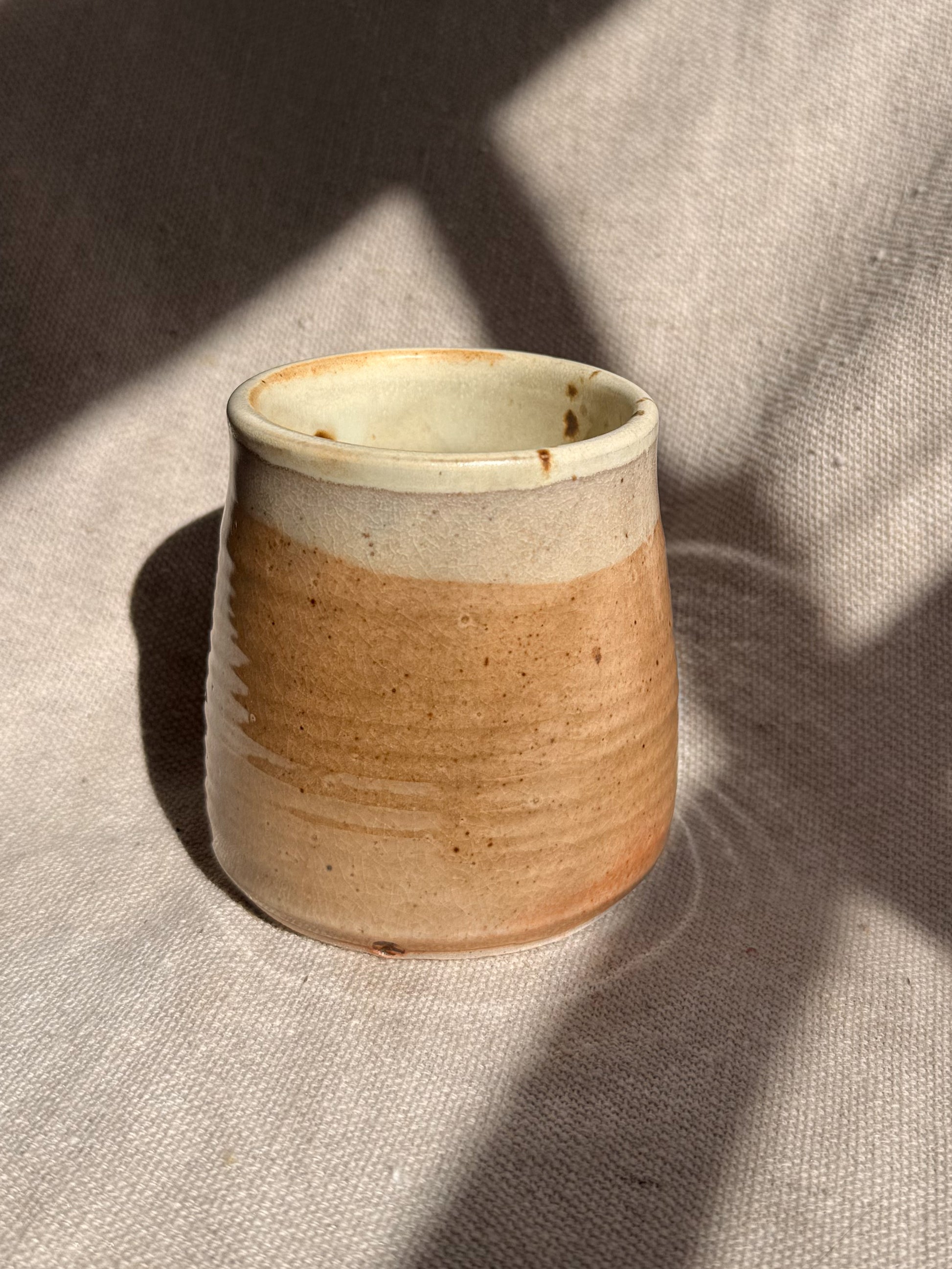 Ceramic cup with two-tone design on a textured surface