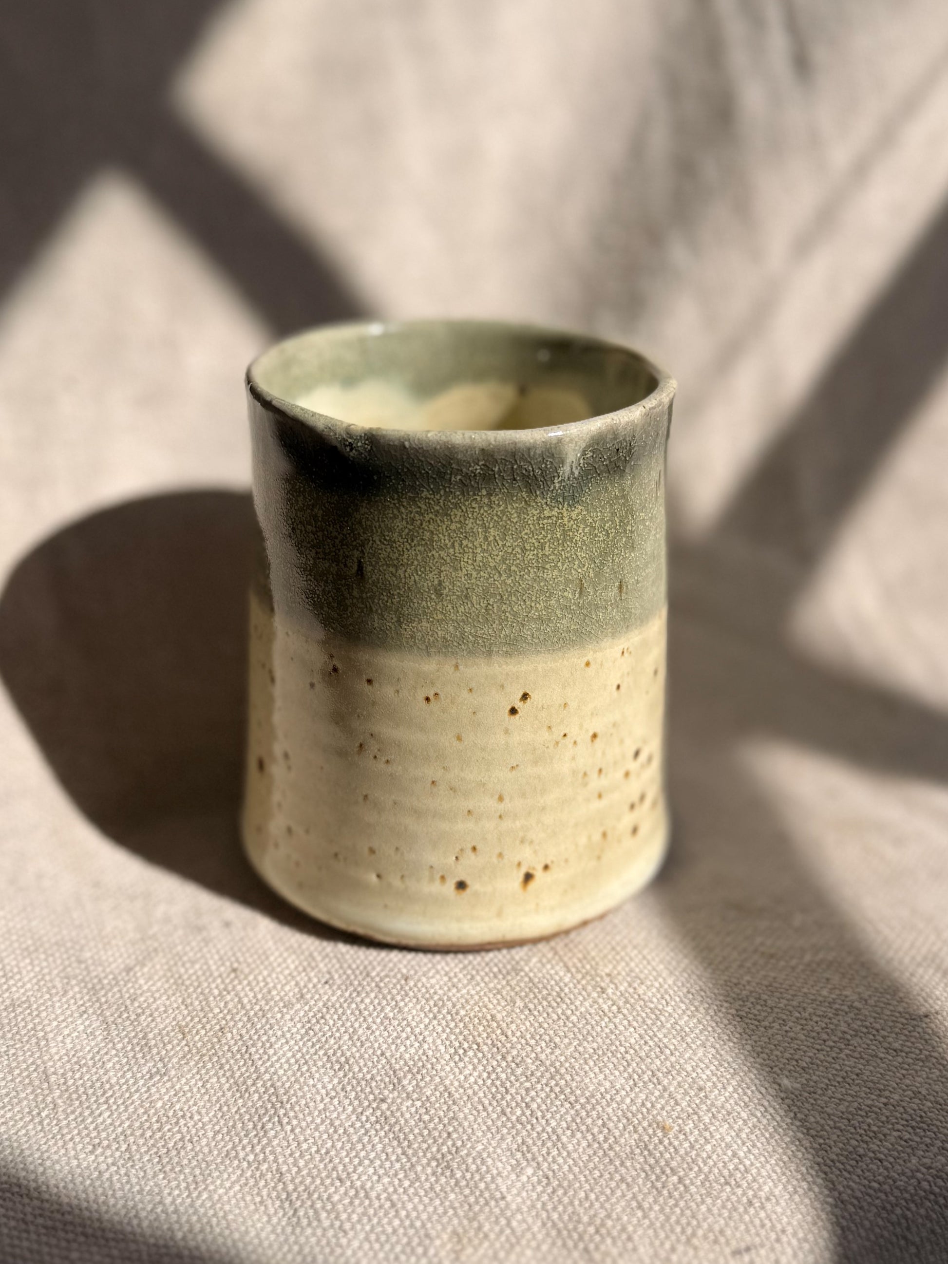 Ceramic cup with two-tone glaze on a textured surface