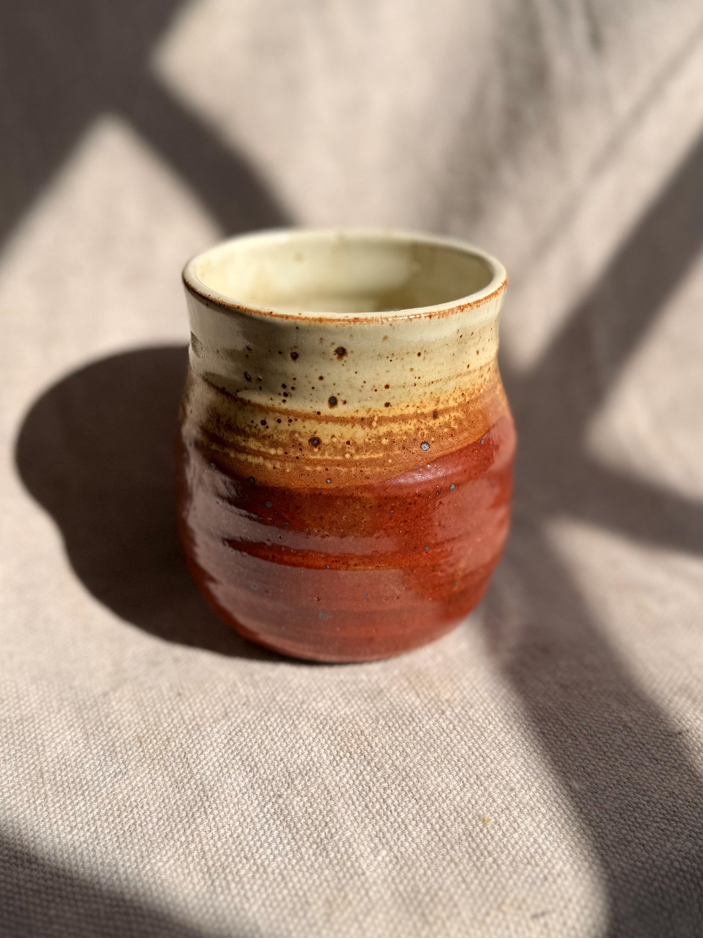 Ceramic cup with two-tone glaze on a textured surface
