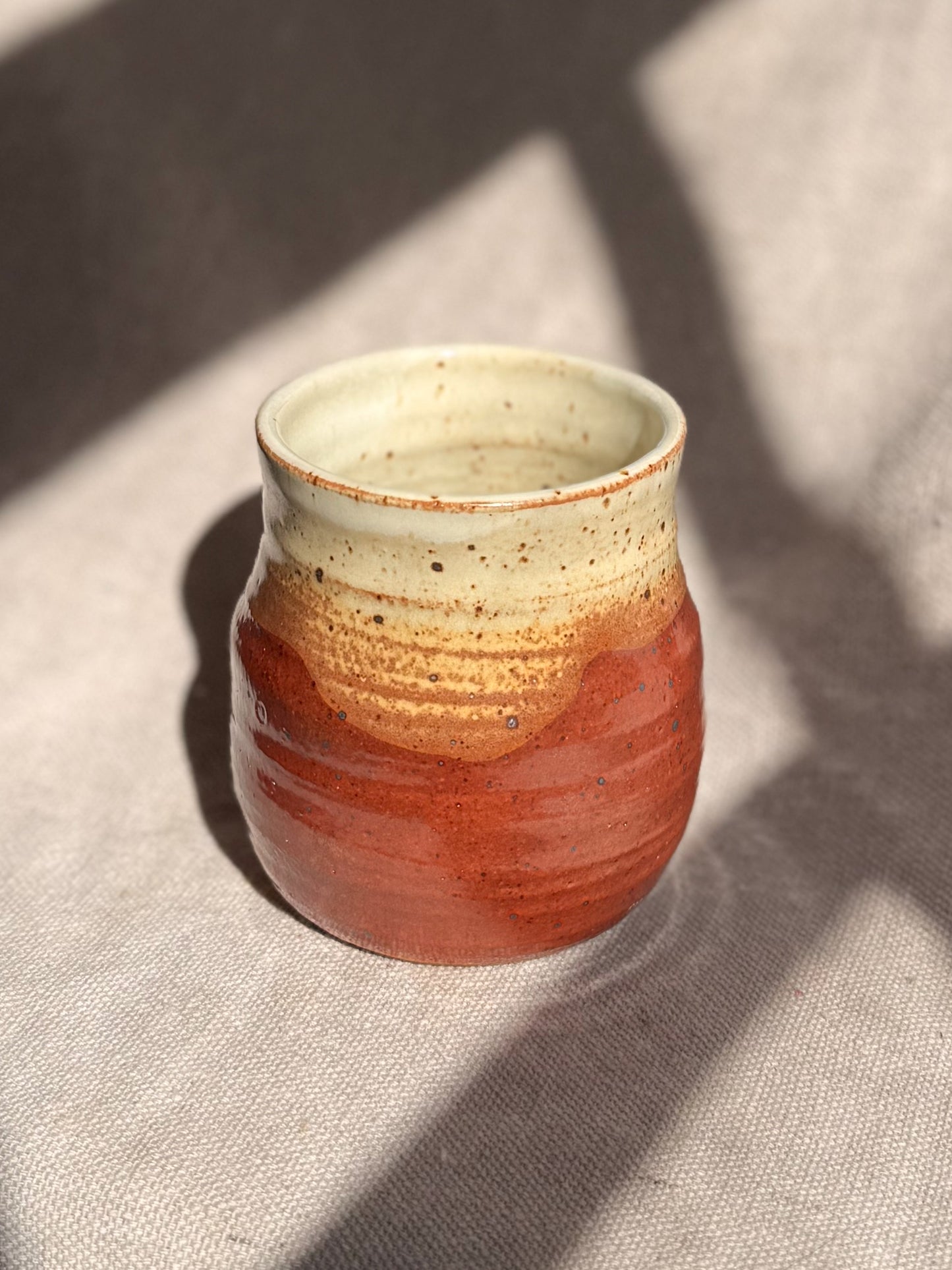 Ceramic cup with two-tone design on a textured surface