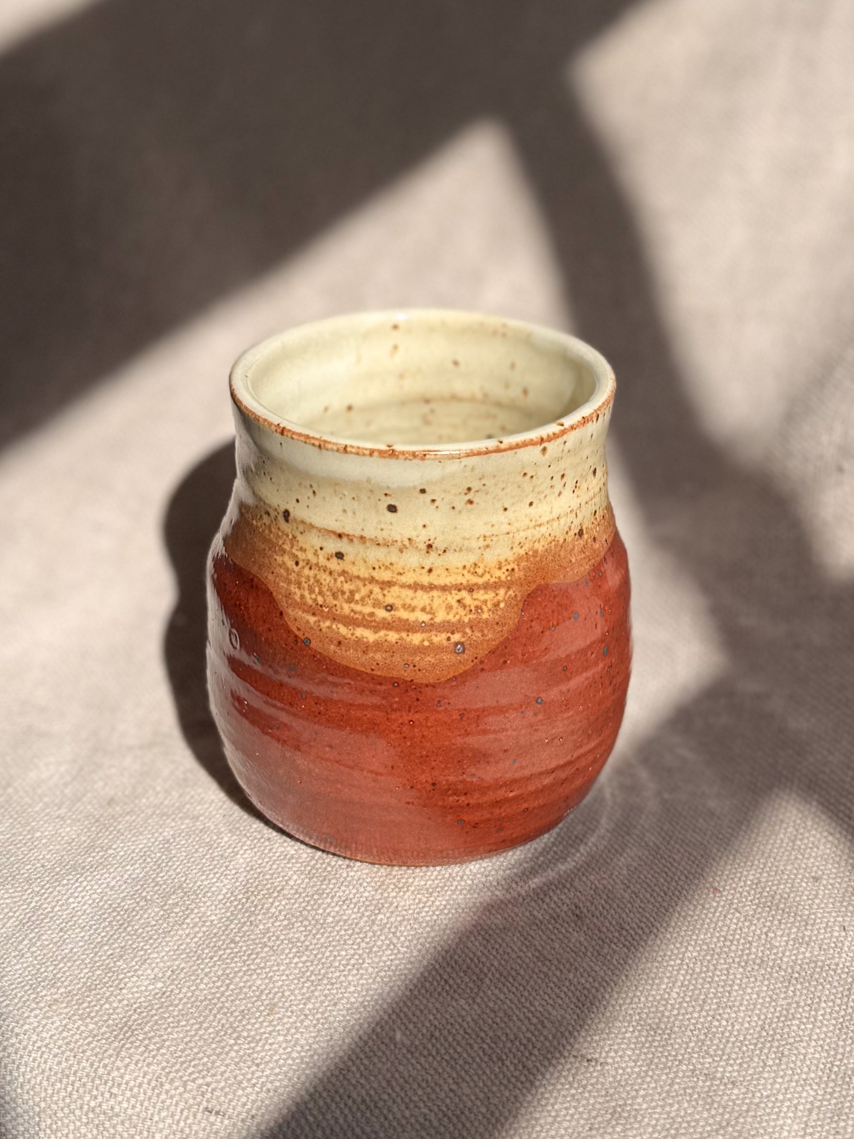 Ceramic cup with two-tone design on a textured surface