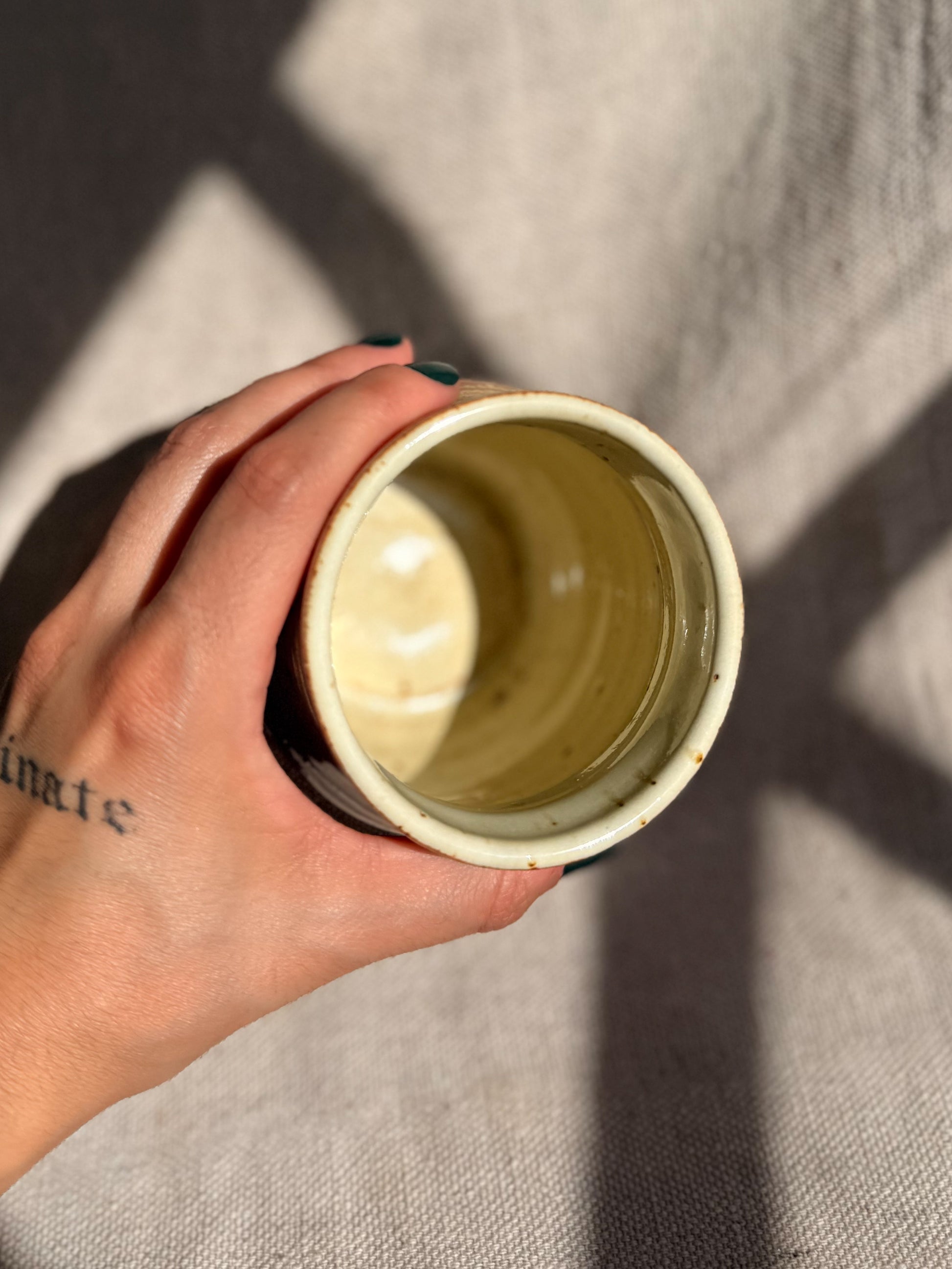 Hand holding a ceramic cup against a textured gray background