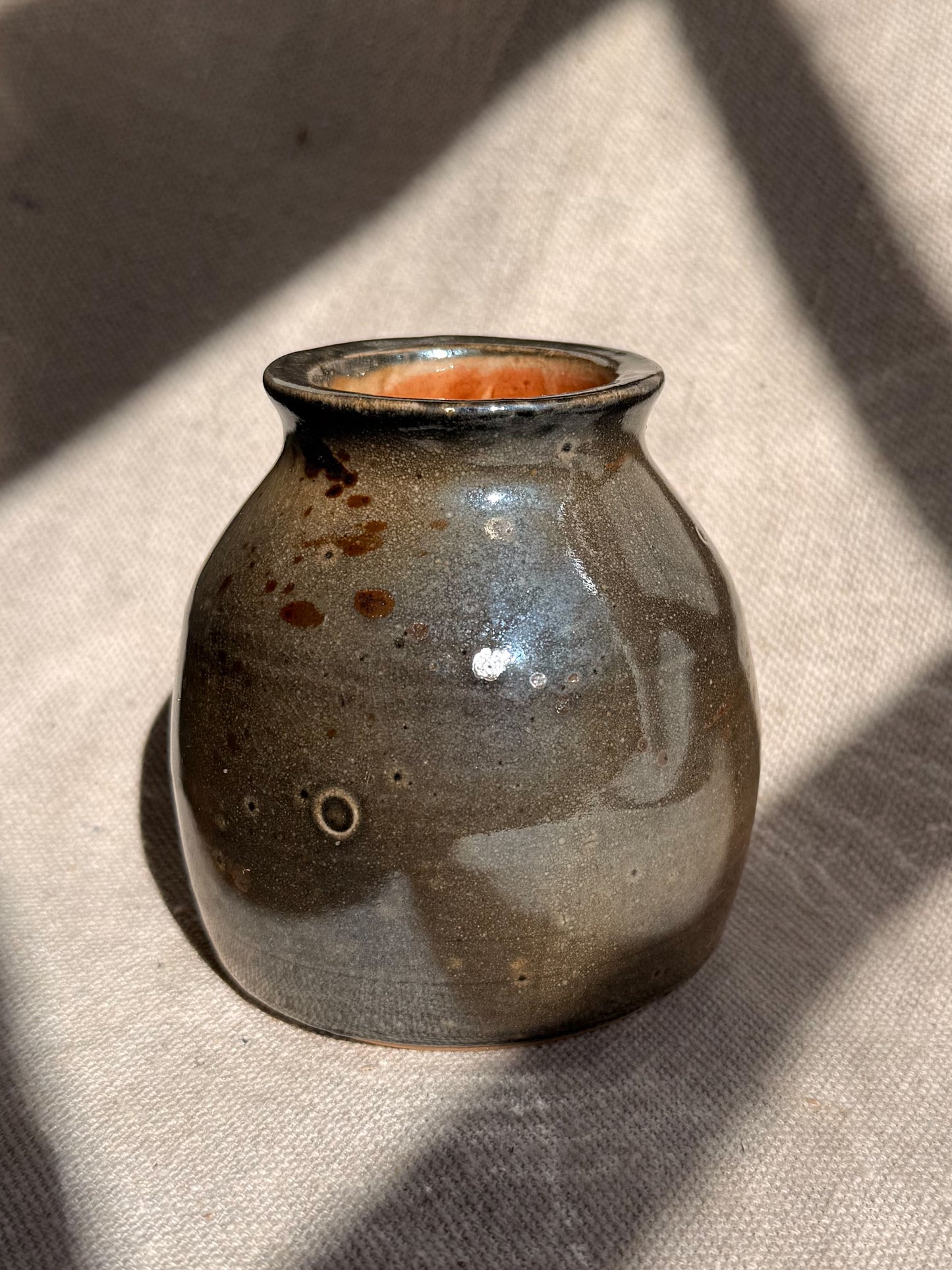 Small ceramic vase with a glossy finish on a textured surface