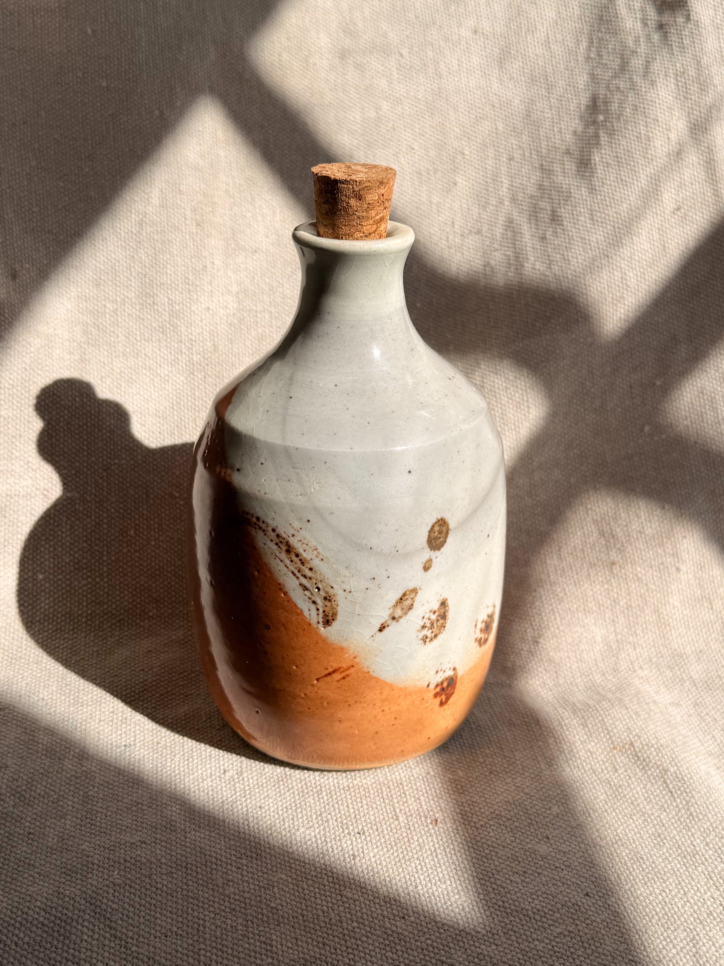 Ceramic bottle with a cork on a textured surface