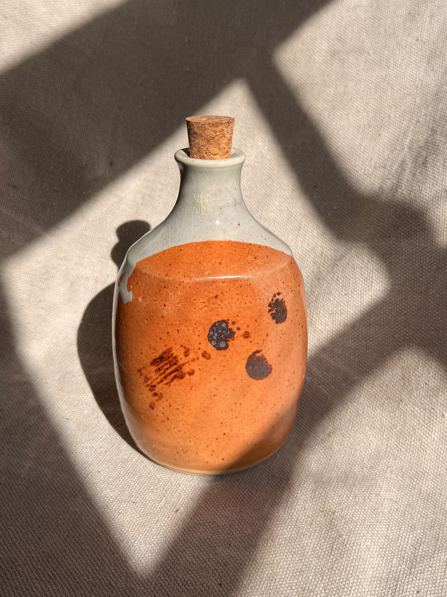 Decorative bottle with orange liquid and cork on a textured surface