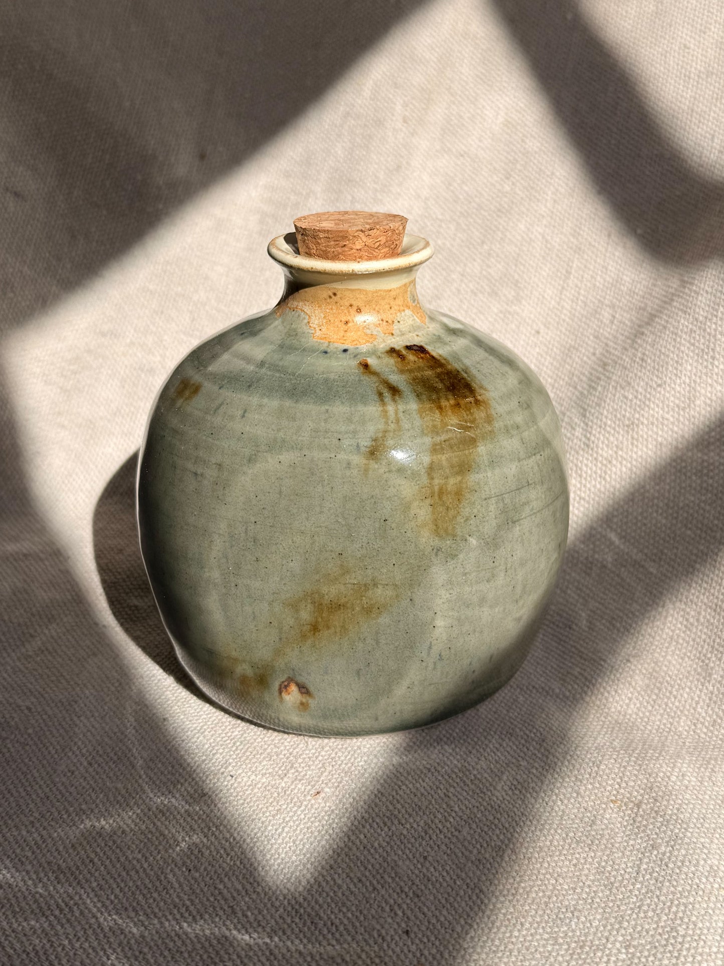 Ceramic bottle with cork stopper on a textured surface