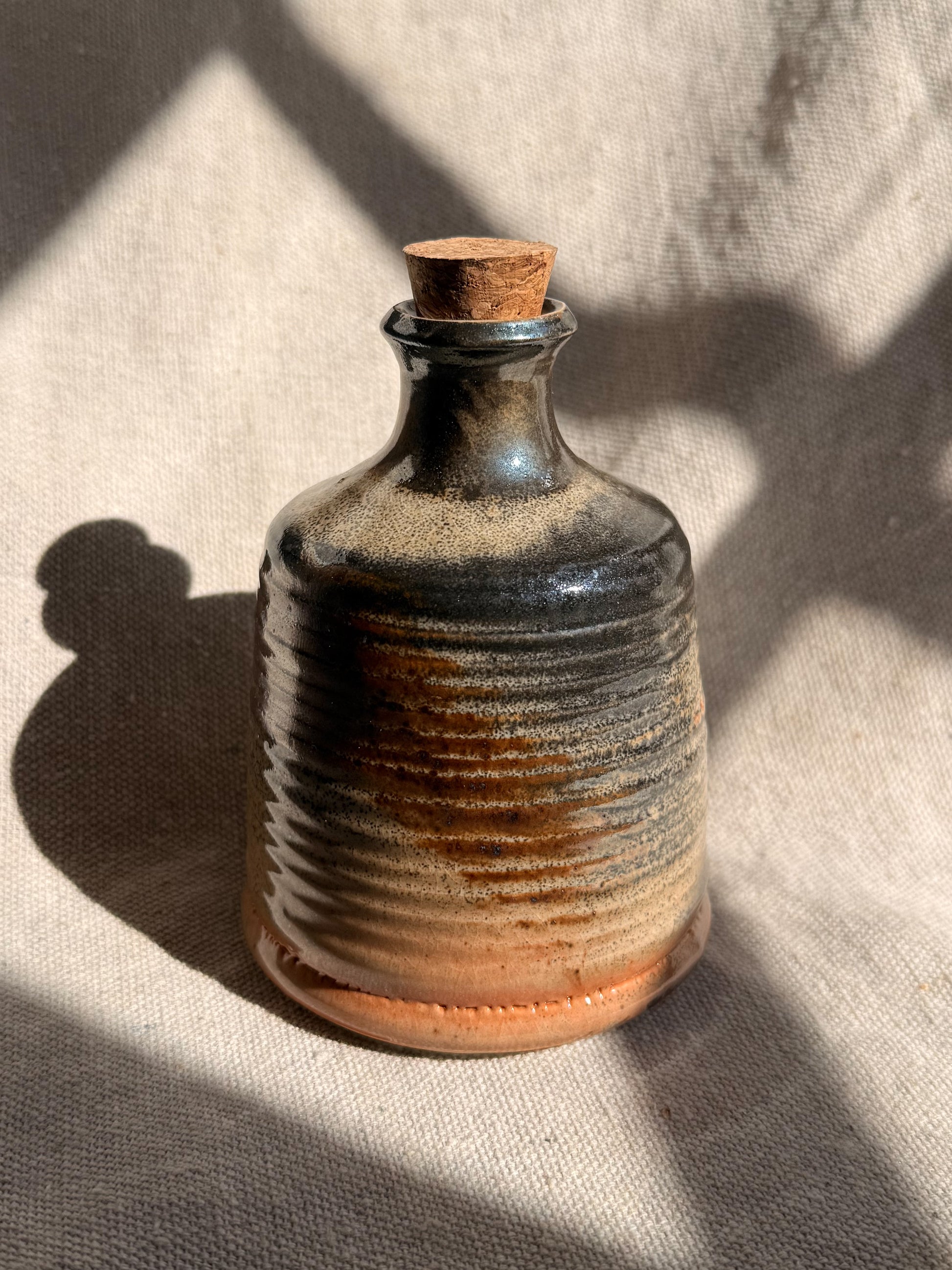 Ceramic bottle with a cork on a textured fabric background