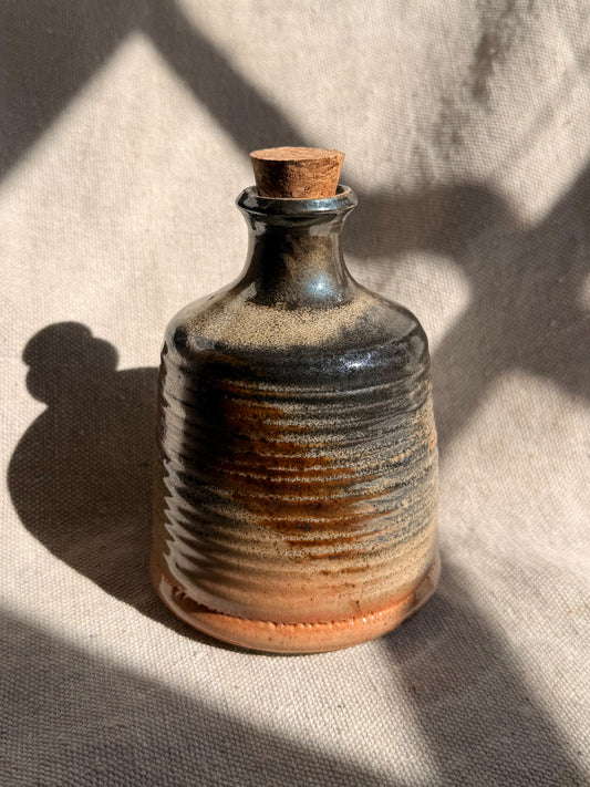 Ceramic bottle with a cork on a textured fabric background