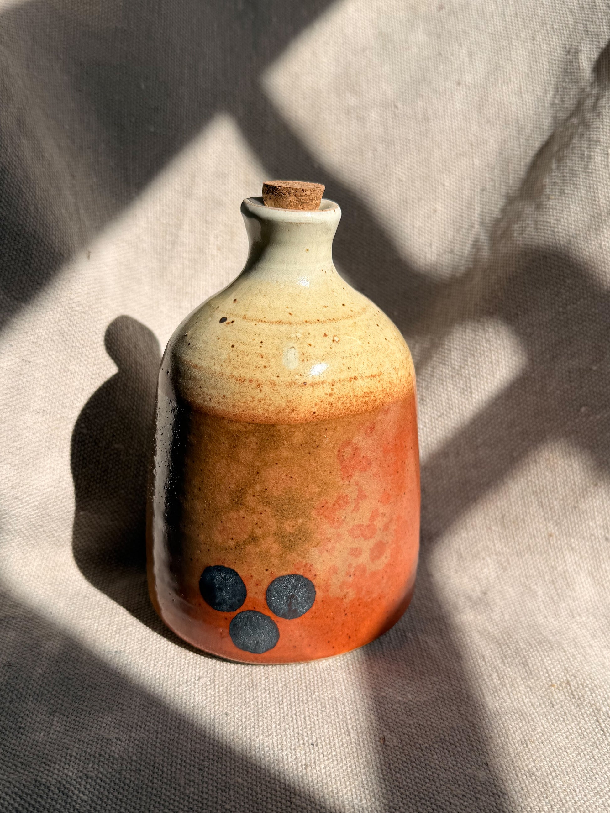Ceramic bottle with a textured surface on a textured fabric background