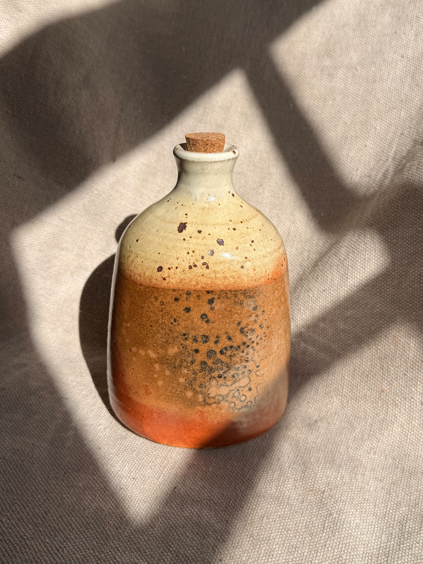 Ceramic bottle with speckled design on a textured surface