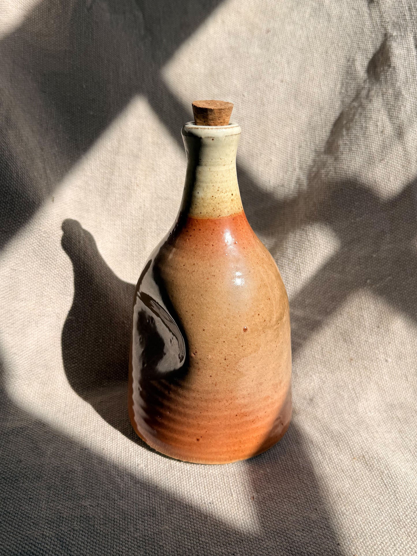 Ceramic bottle with a cork on a textured fabric background
