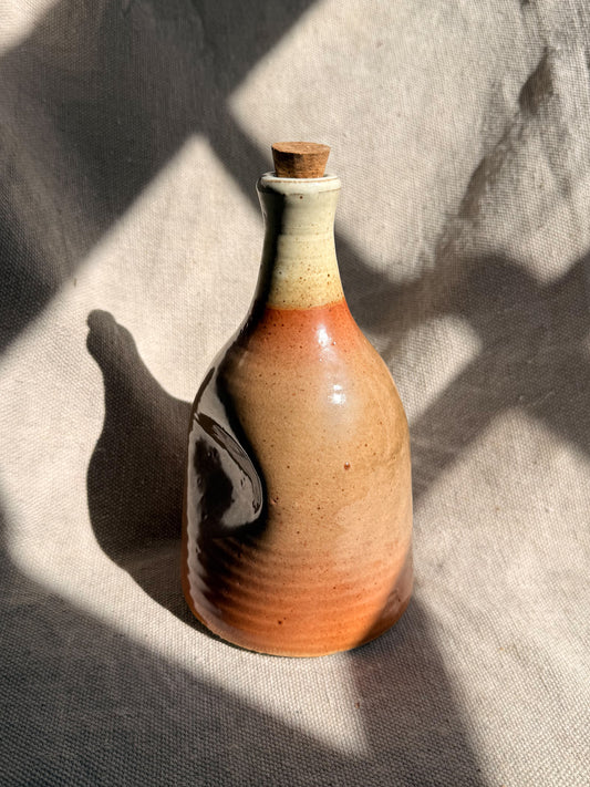 Ceramic bottle with a cork on a textured fabric background