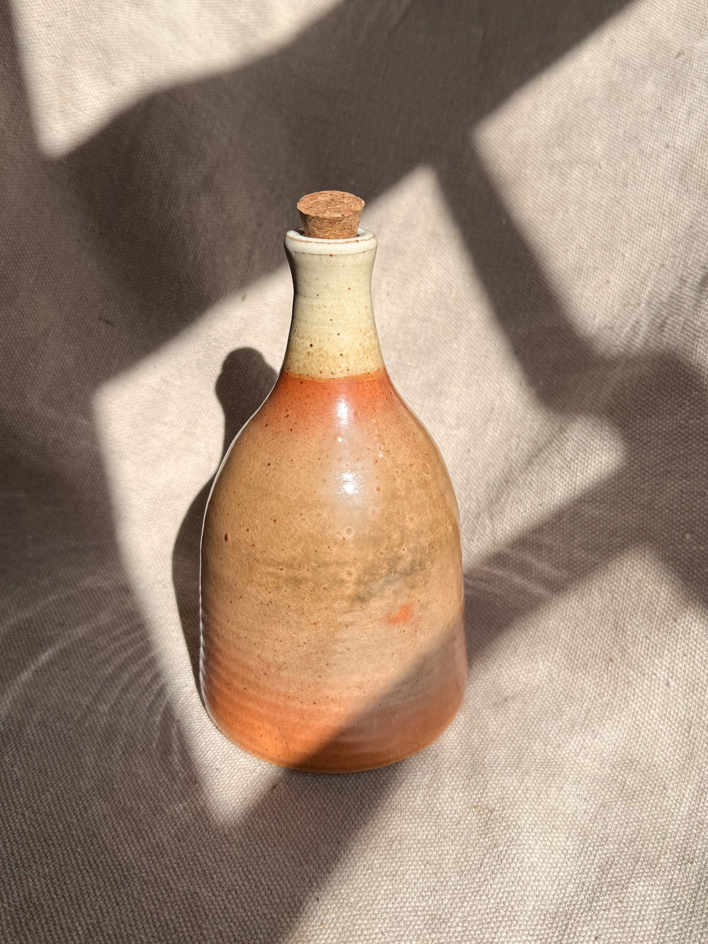 Ceramic bottle with a cork stopper on a textured surface