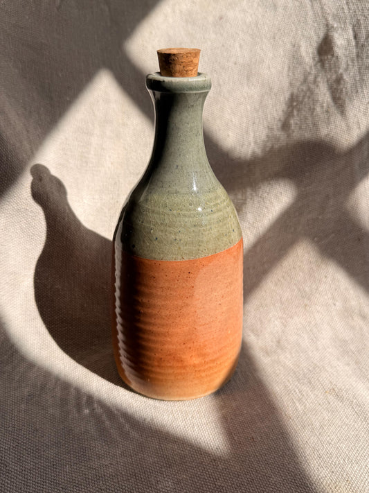 Ceramic bottle with a cork stopper on a textured surface