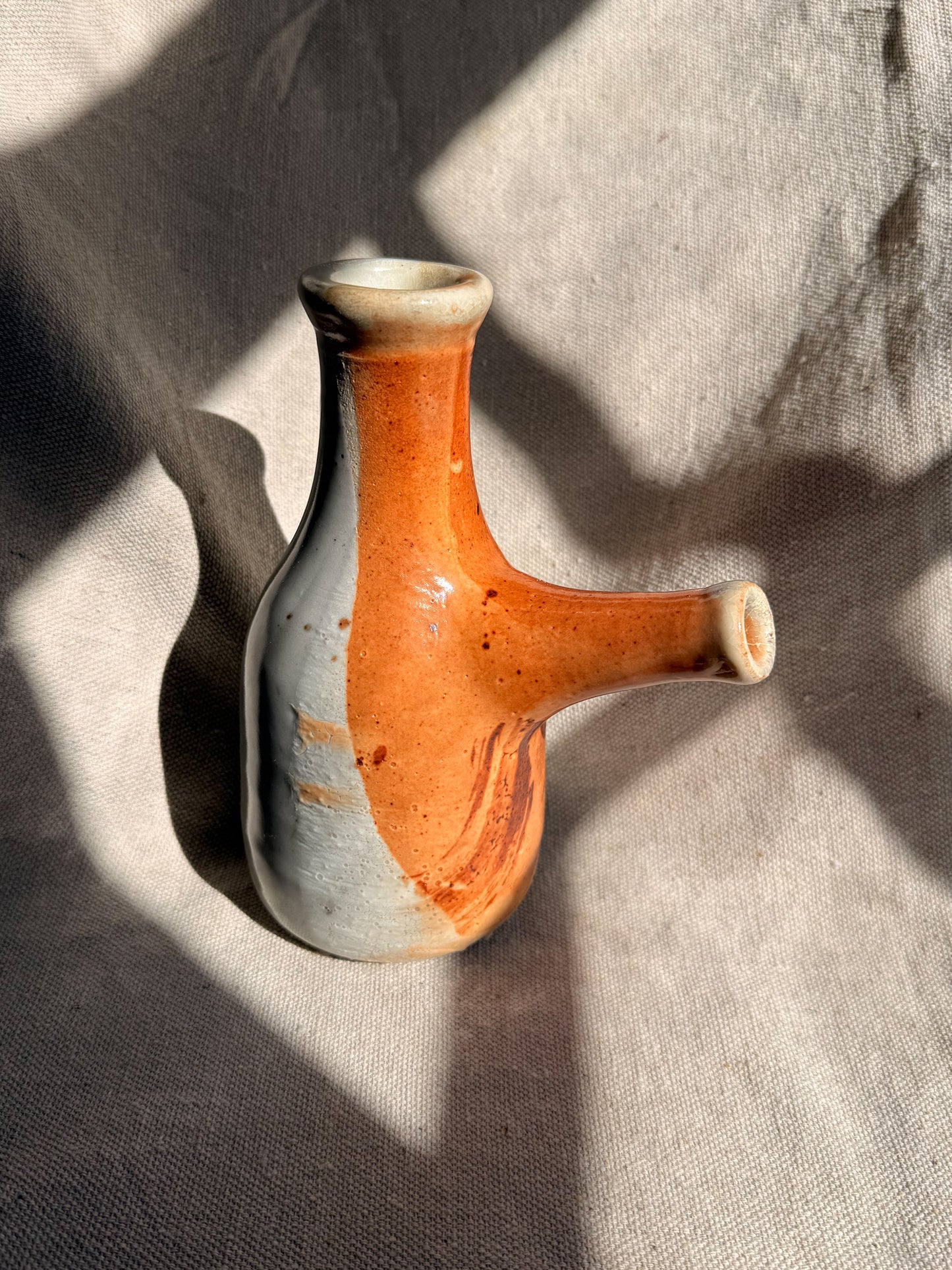 Ceramic vase with orange and gray gradient on a textured surface