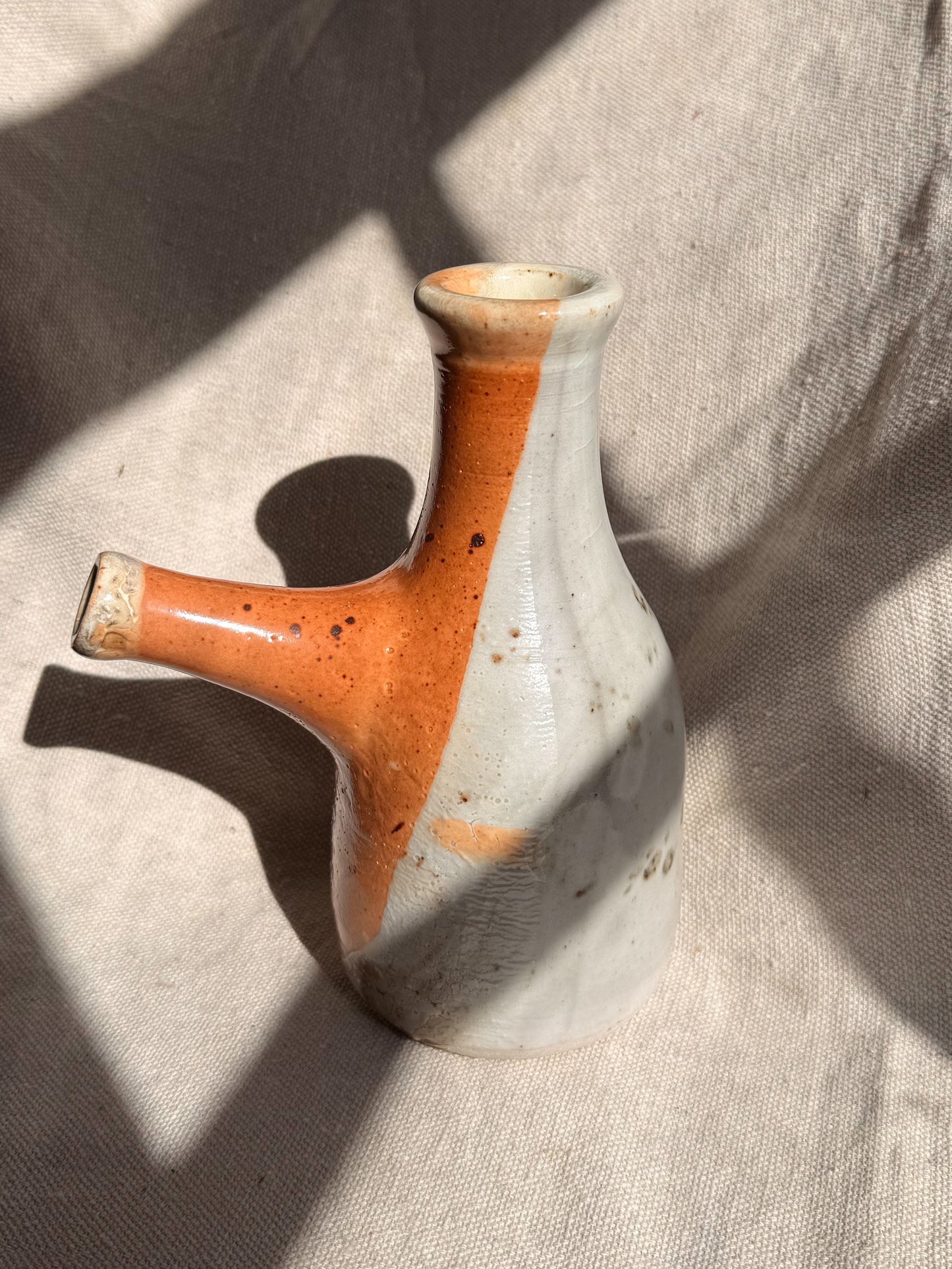 Ceramic vase with brown and white speckled design on a textured beige surface
