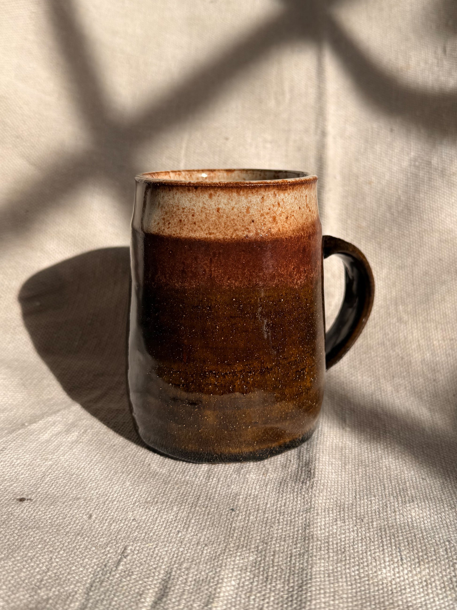 brown ceramic mug with red dot on it 