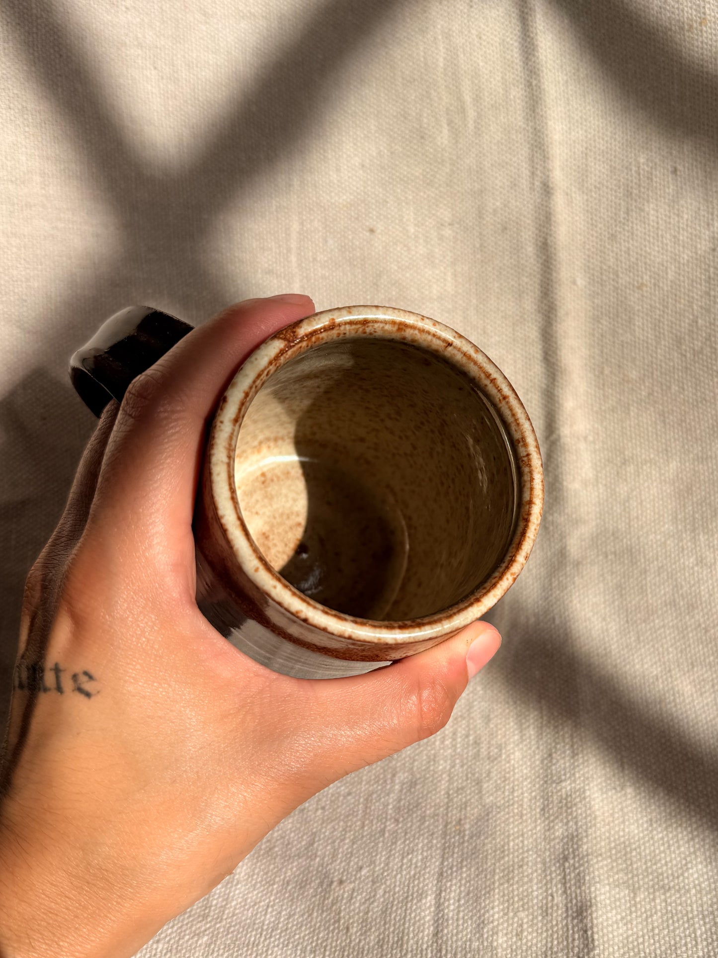 brown ceramic mug with red dot on it 