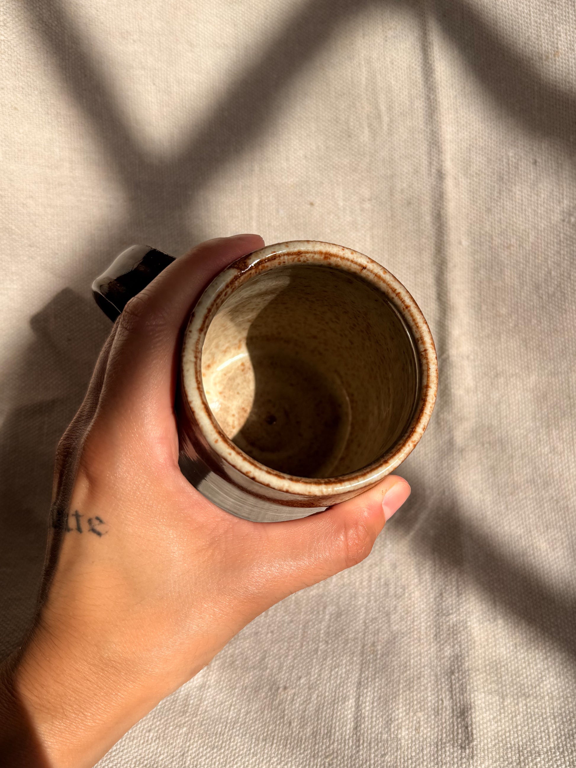 brown ceramic mug with black dot on it 
