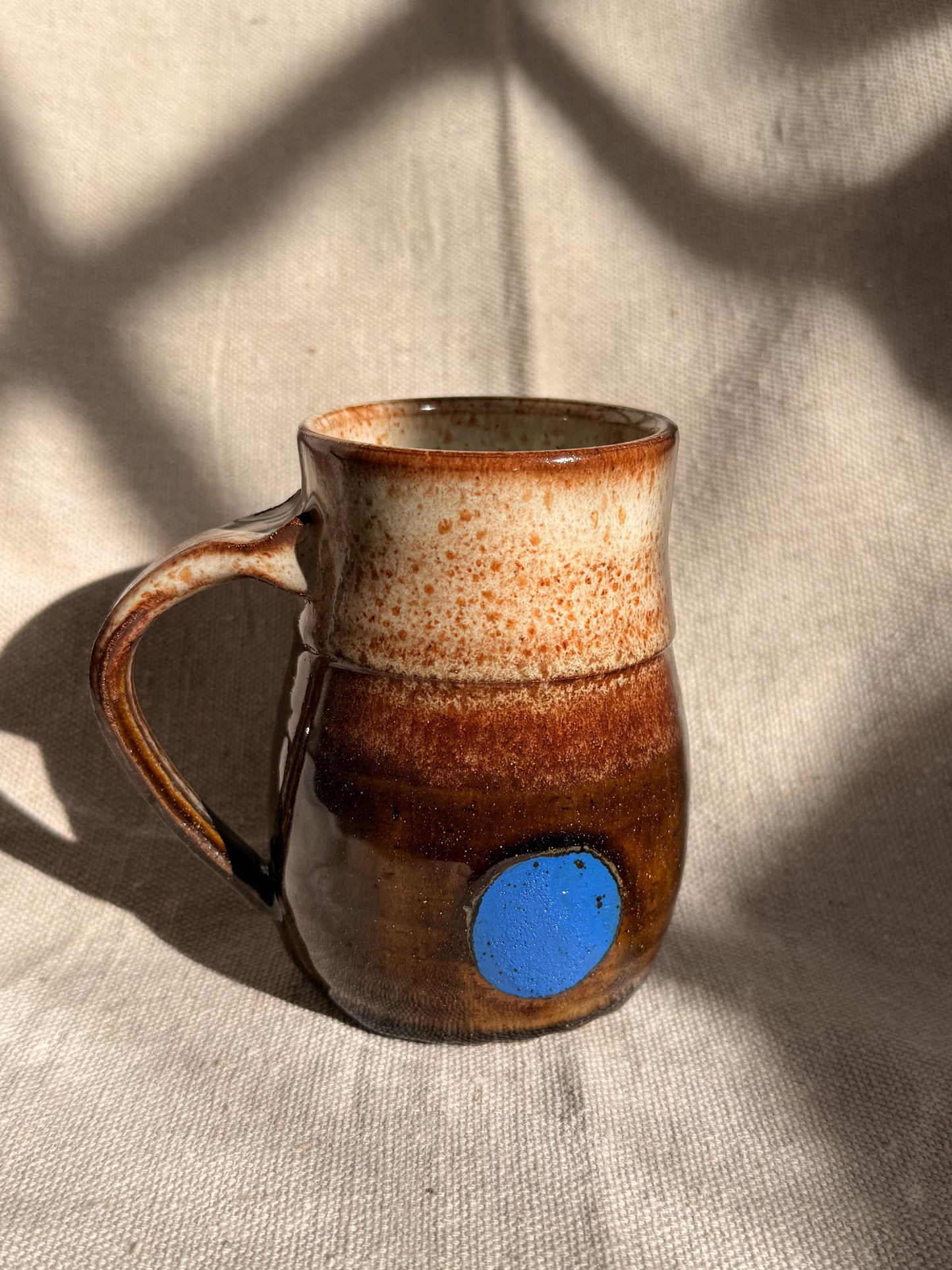 brown ceramic mug with blue dot 