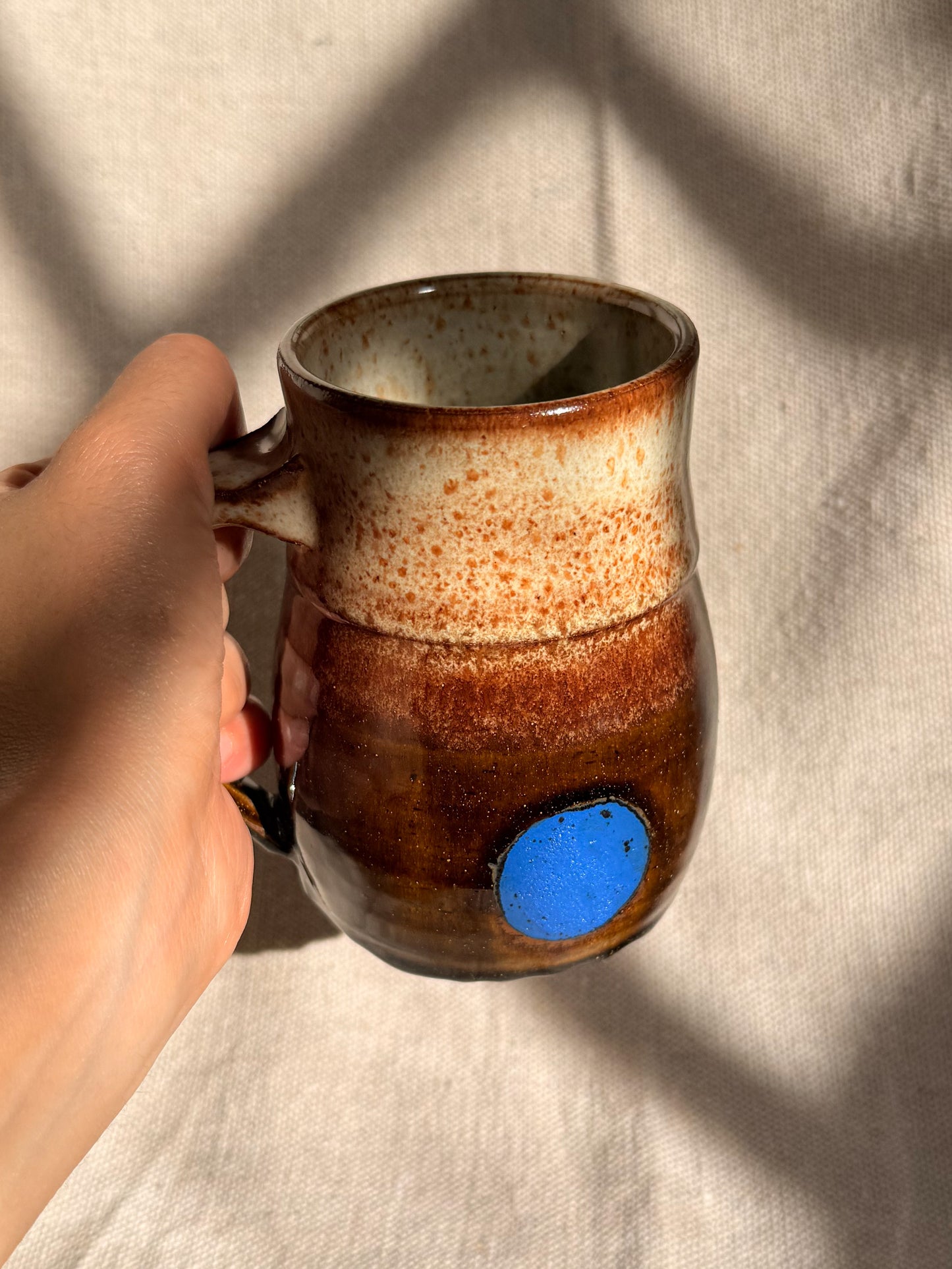 brown ceramic mug with blue dot 