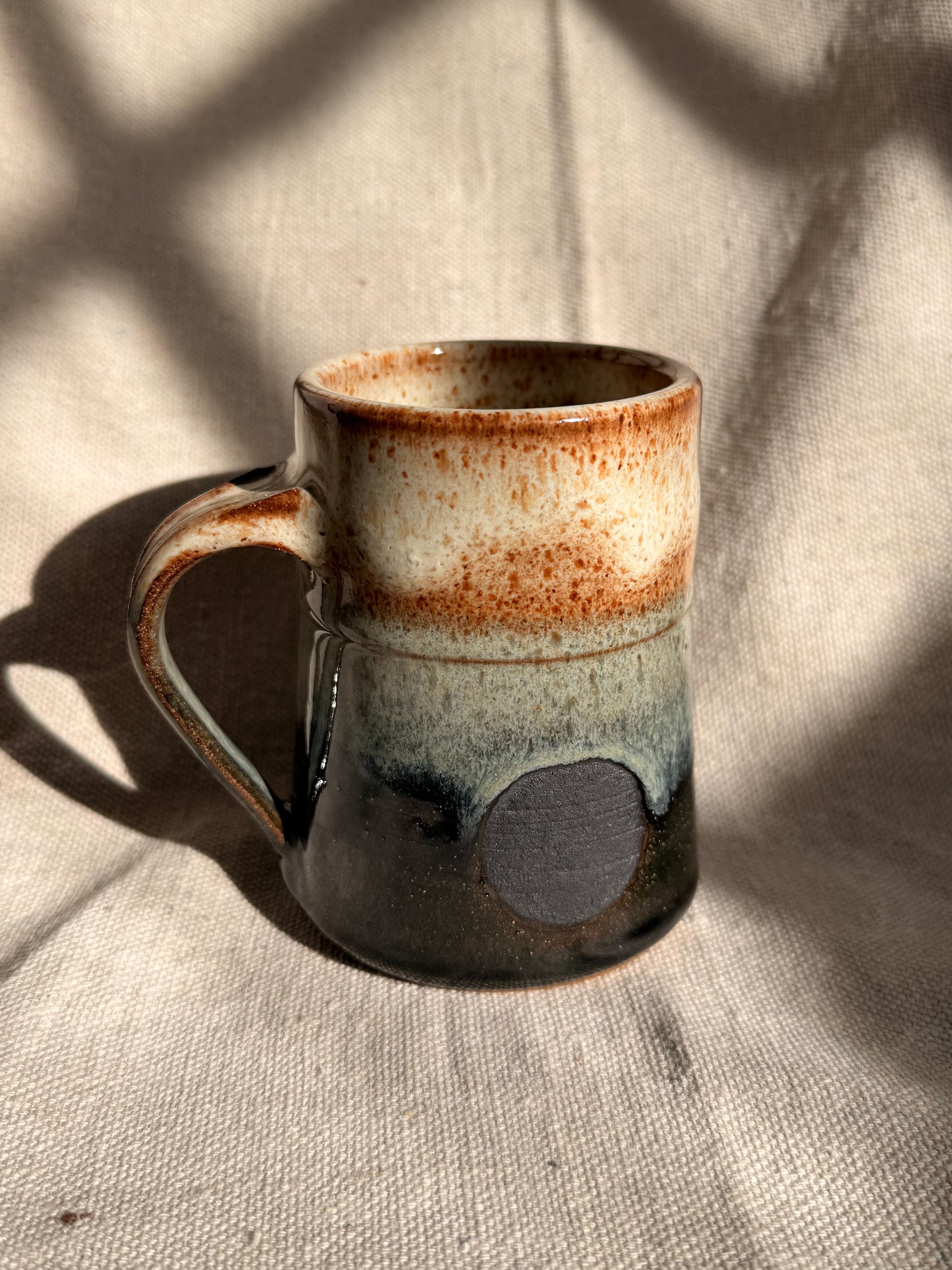 beige ceramic mug with black dot 