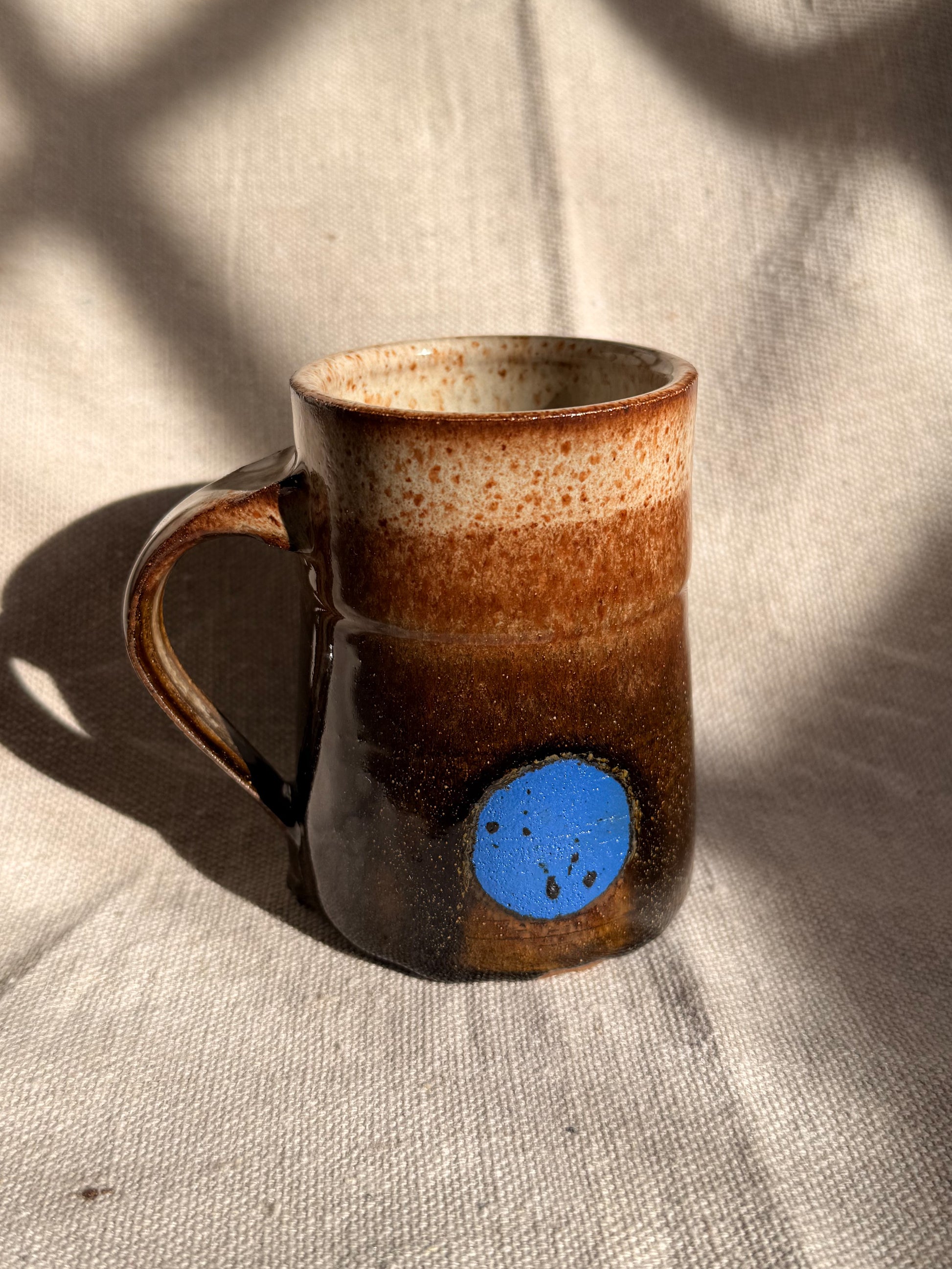 brown ceramic mug with blue dot 
