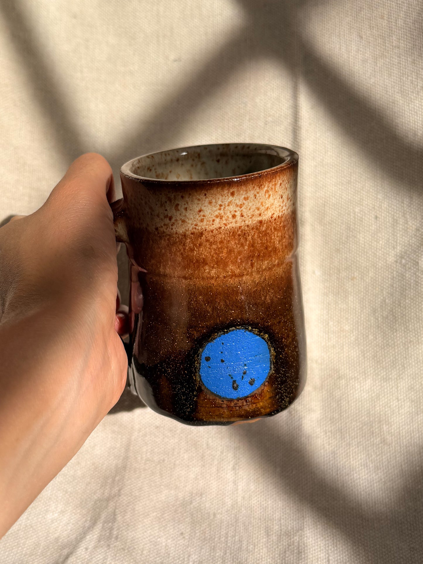 brown ceramic mug with blue dot 