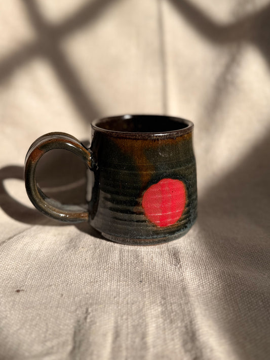 brown ceramic mug with red dot 