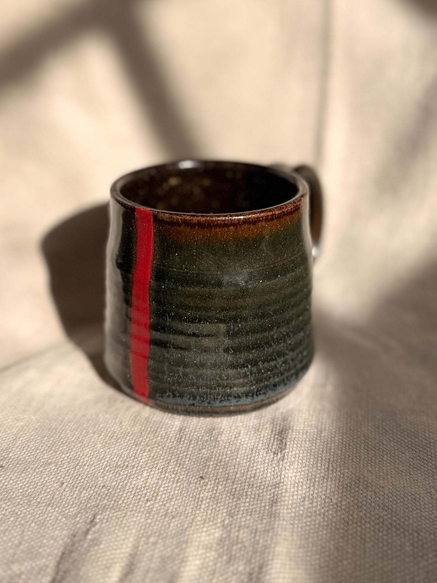 brown ceramic mug with red dot 