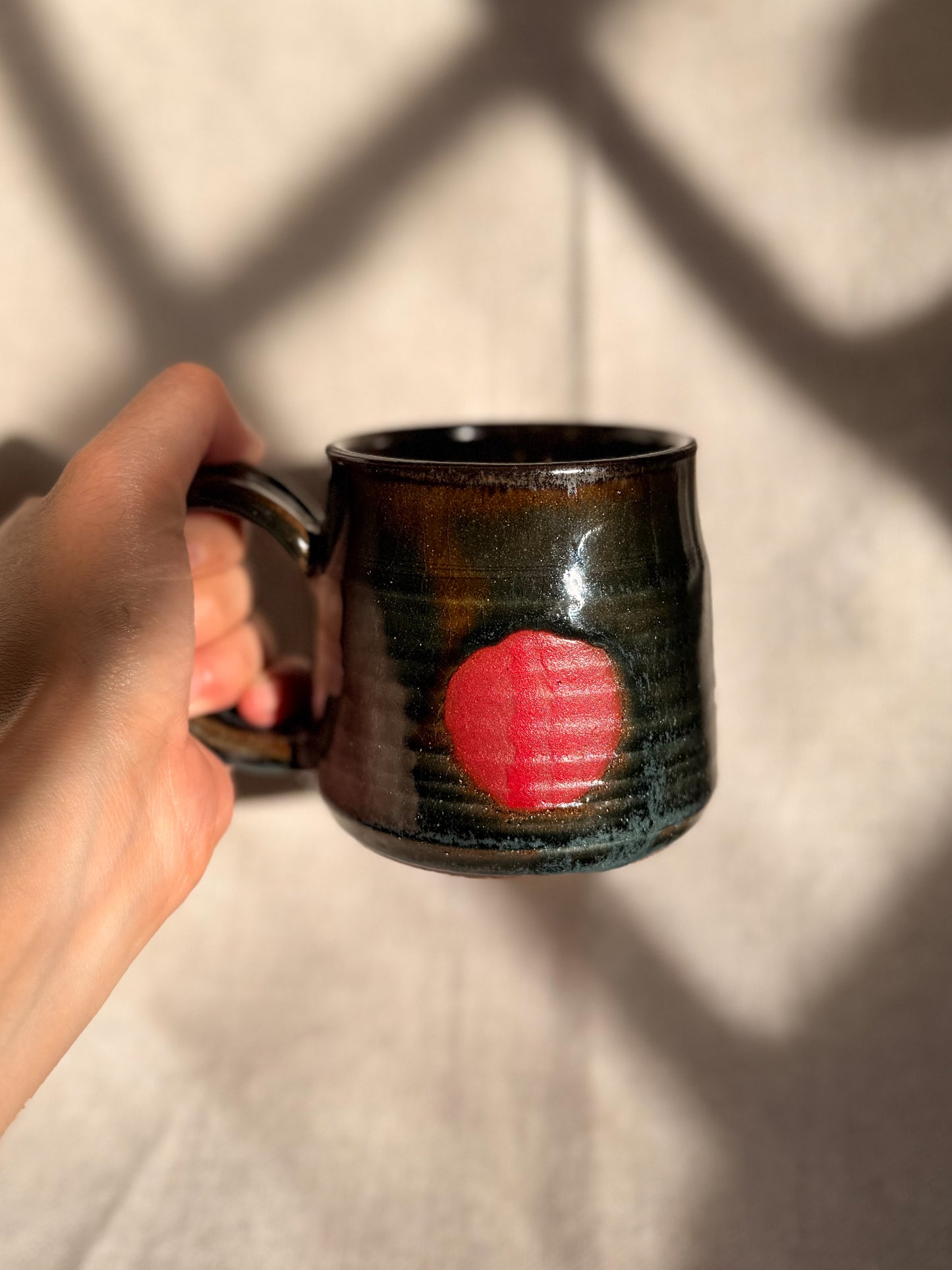 brown ceramic mug with red dot 