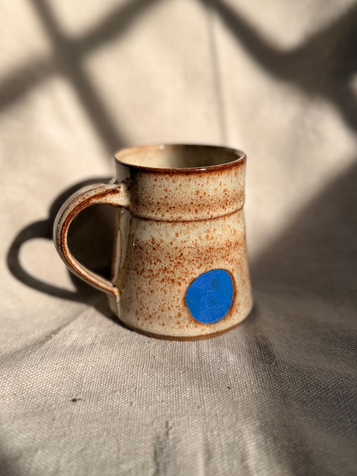 beige ceramic mug with blue dot 