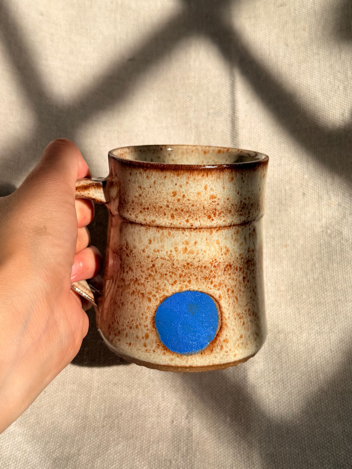 beige ceramic mug with blue dot 