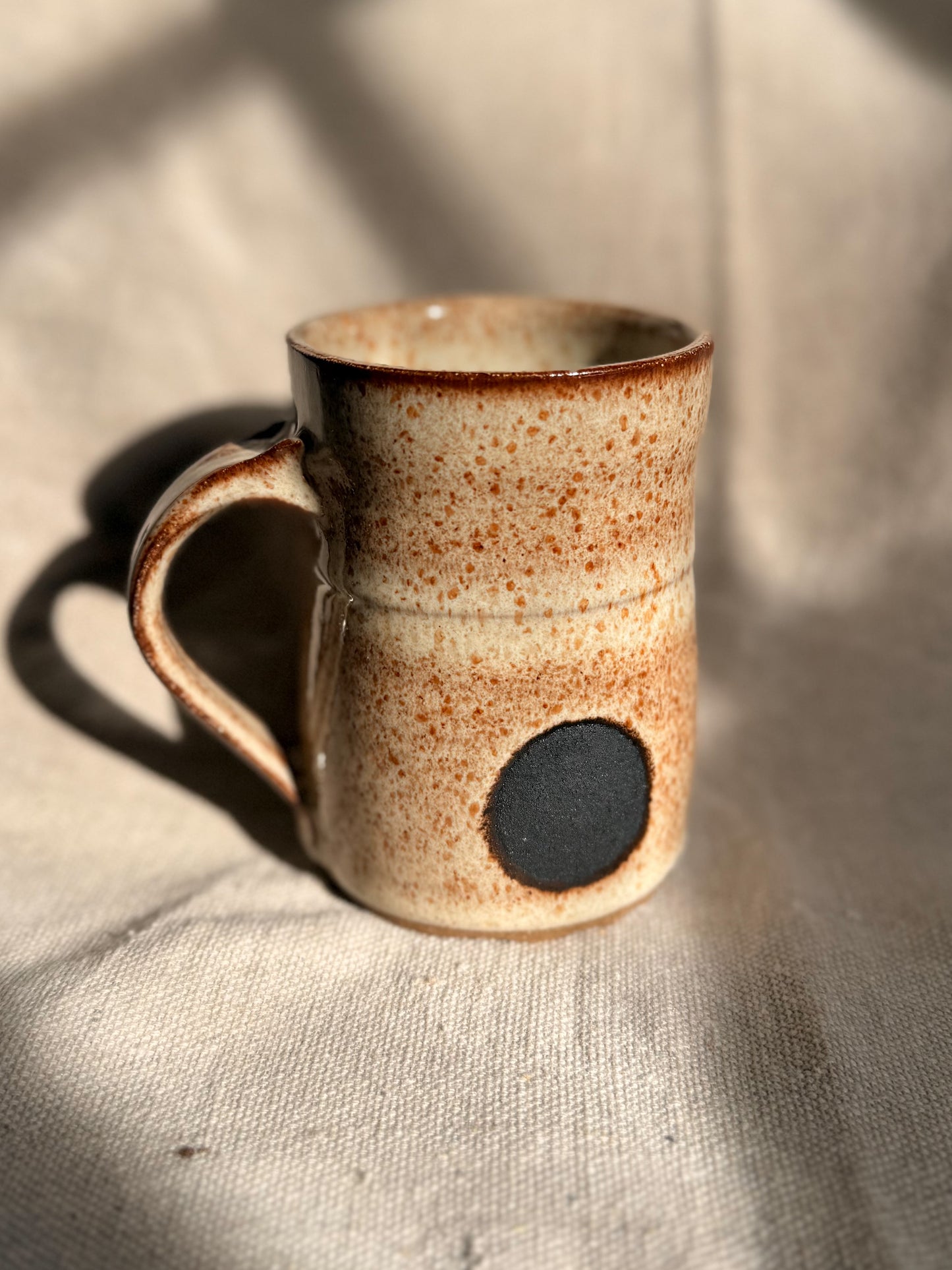 beige ceramic mug with black dot 