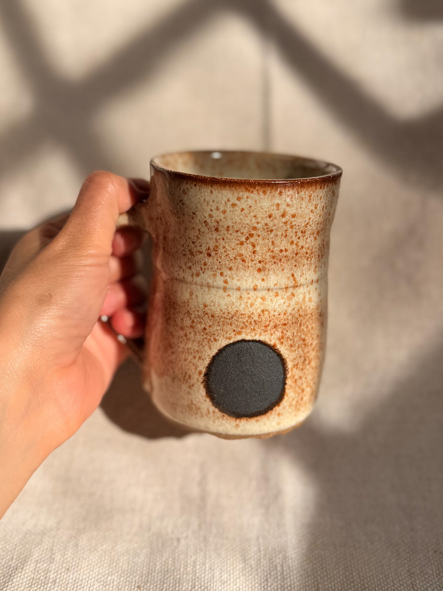 beige ceramic mug with black dot 