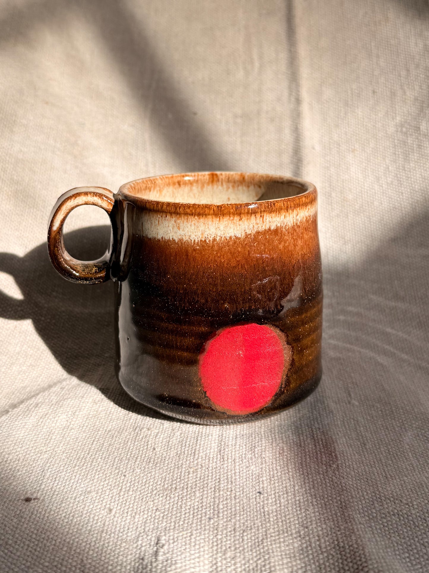 brown ceramic mug with red dot