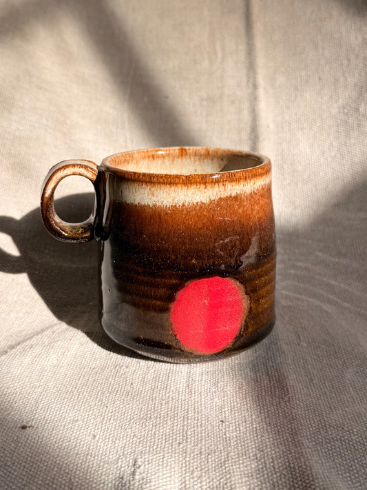 brown ceramic mug with red dot